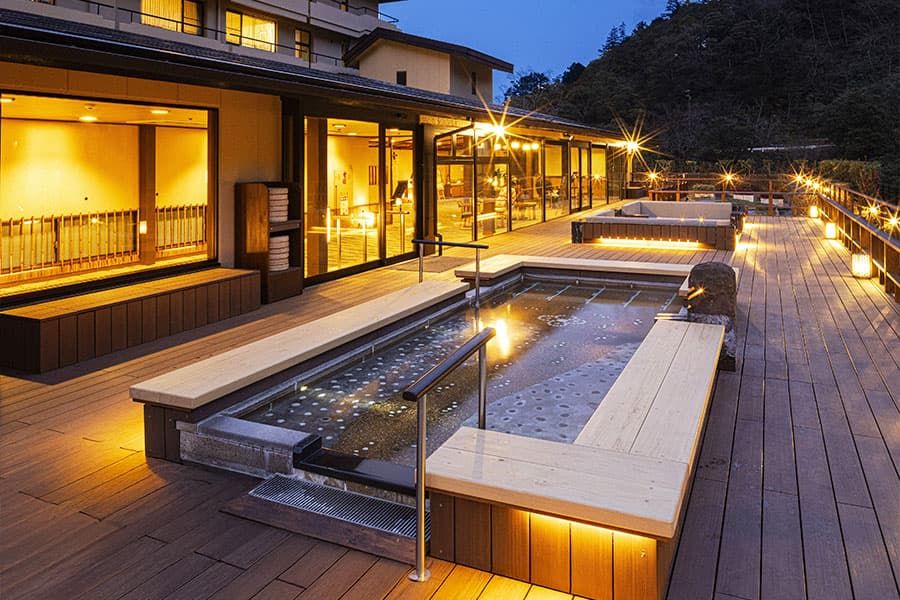 広々とした外に設置された足湯。背後には湯坂山が見える。