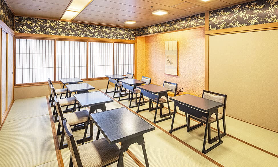 和室の個室。中央には少人数用のテーブルが置かれ、大きな窓があり、外には緑豊かな景色が広がっている。
