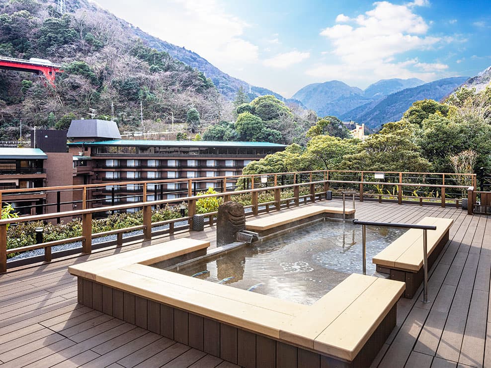 広々とした外に設置された足湯。背後には湯坂山が見える。