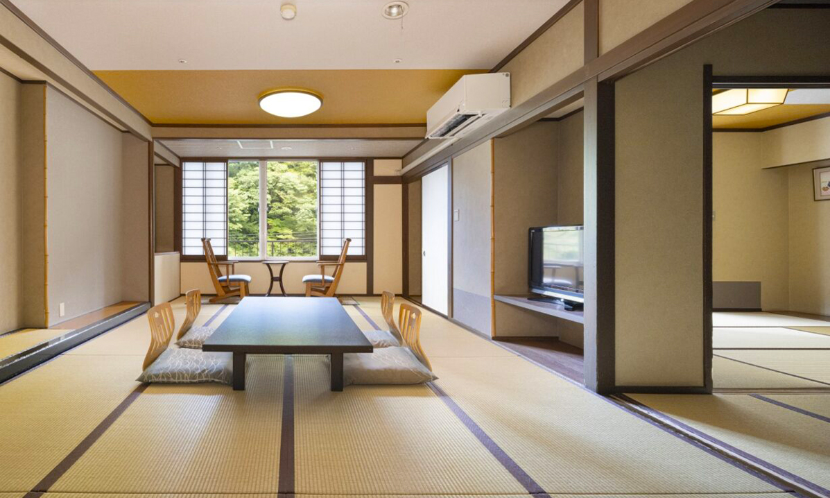 和室のリビングで、座椅子とテーブルとソファがあるシンプルで温かみのある客室